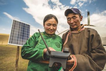 Two farmers use a sms forecasting system device. 