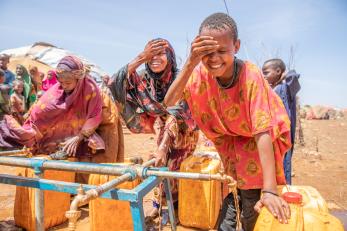 Children take a drink and wash their faces at a mercy corps water point in the displacement camp near baidoa, somalia.