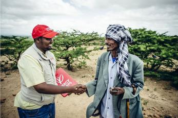 Mercy Corps employee shaking hands with a program participant
