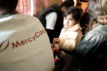 A small child in Georgia next to a Mercy Corps team member