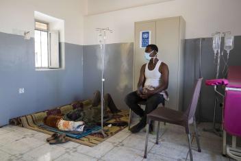 Adom Beyet, a patient at the Um Rakuba health center, waits to see a doctor while another patient receives treatment.