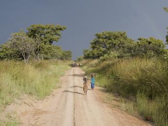 Landscape in rural uganda with two villagers walking down a dirt road