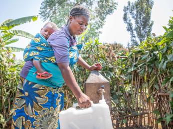 A farmer and mother collects water with her 1 year-old son