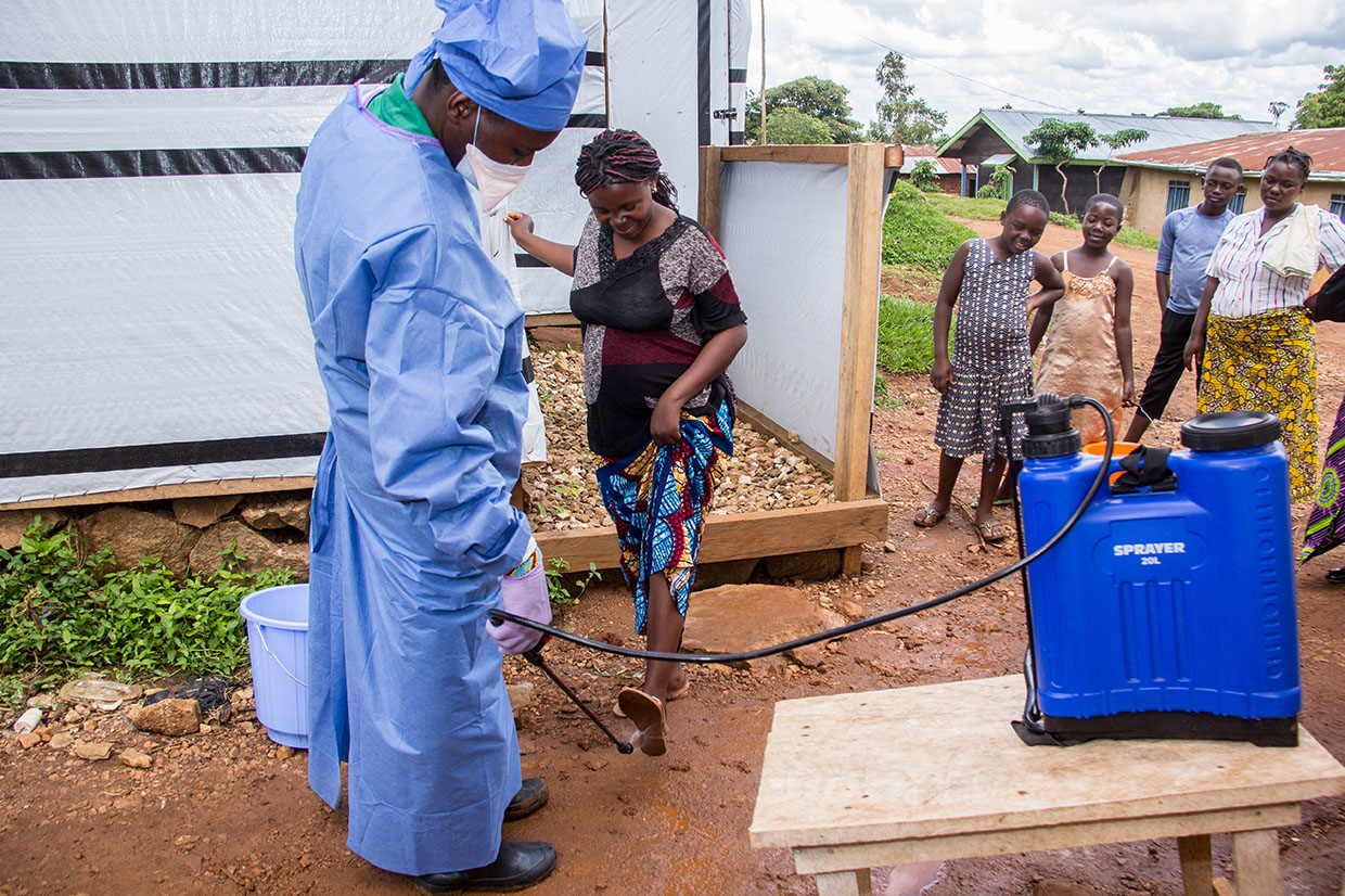 Mercy Corps supports the Malepe Health Center in DRC with chlorine and hand washing kits to disinfect hands before entering. This measure is very effective for the prevention of Ebola. Kavira, 23, pregnant with her first child, comes to the health center for an antenatal clinic. Her feet are disinfected before entering. Photo: Rudy Nkombo/Mercy Corps