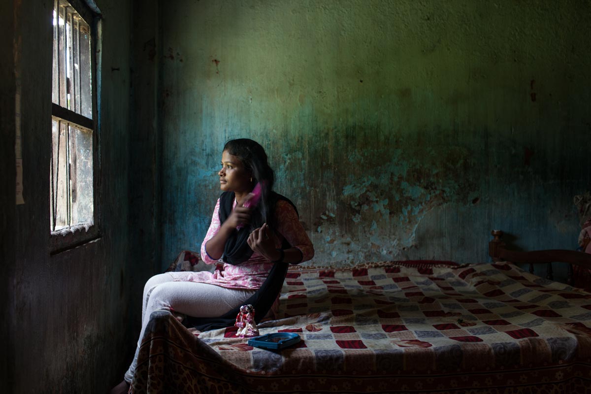 Teen girl in India sitting on her bed and brushing her hair