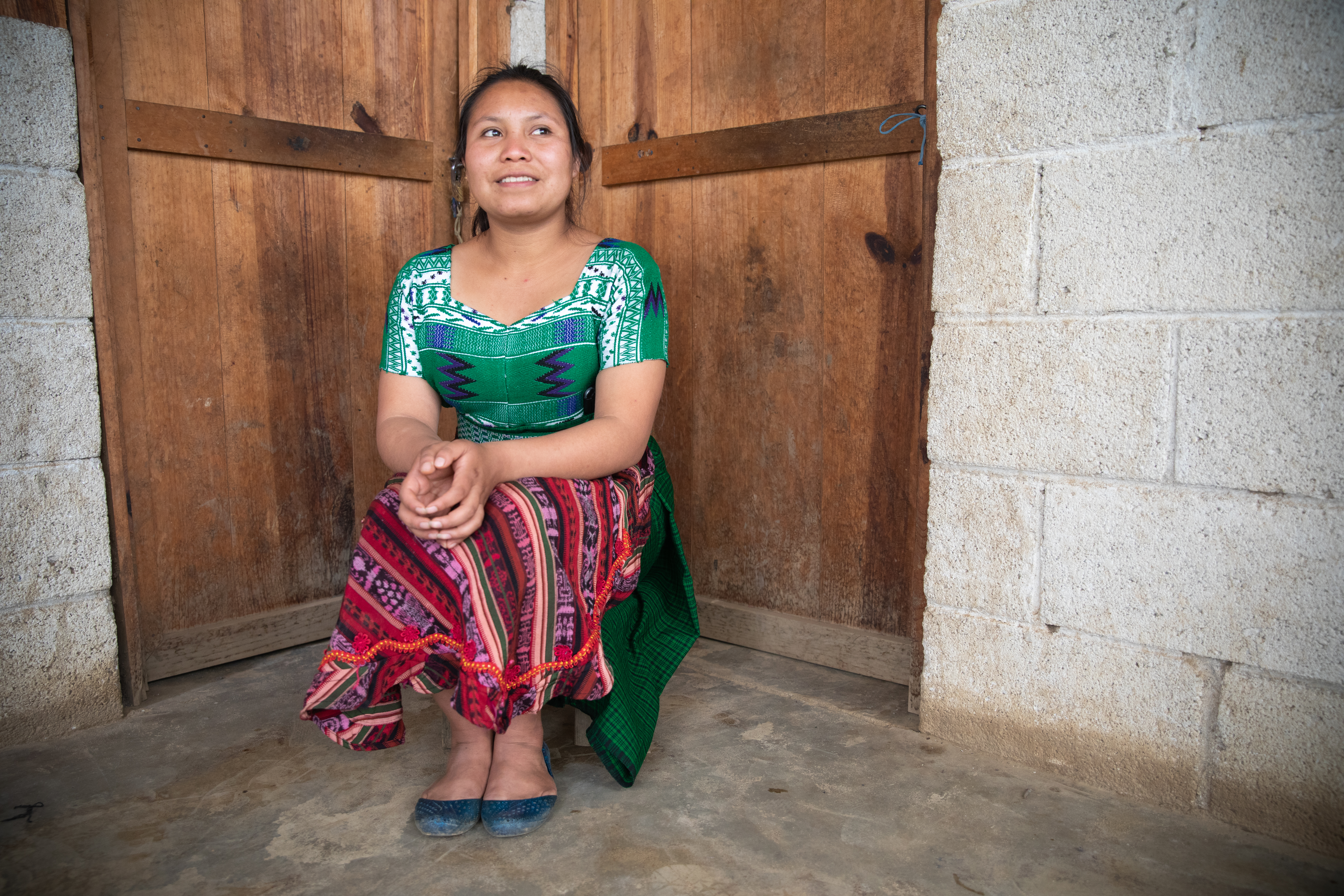 Young woman sitting in corner of room, in front of two doors.