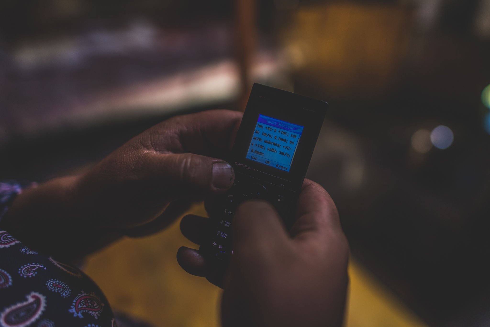 A pair of hands uses a mobile phone to send an SMS text. 