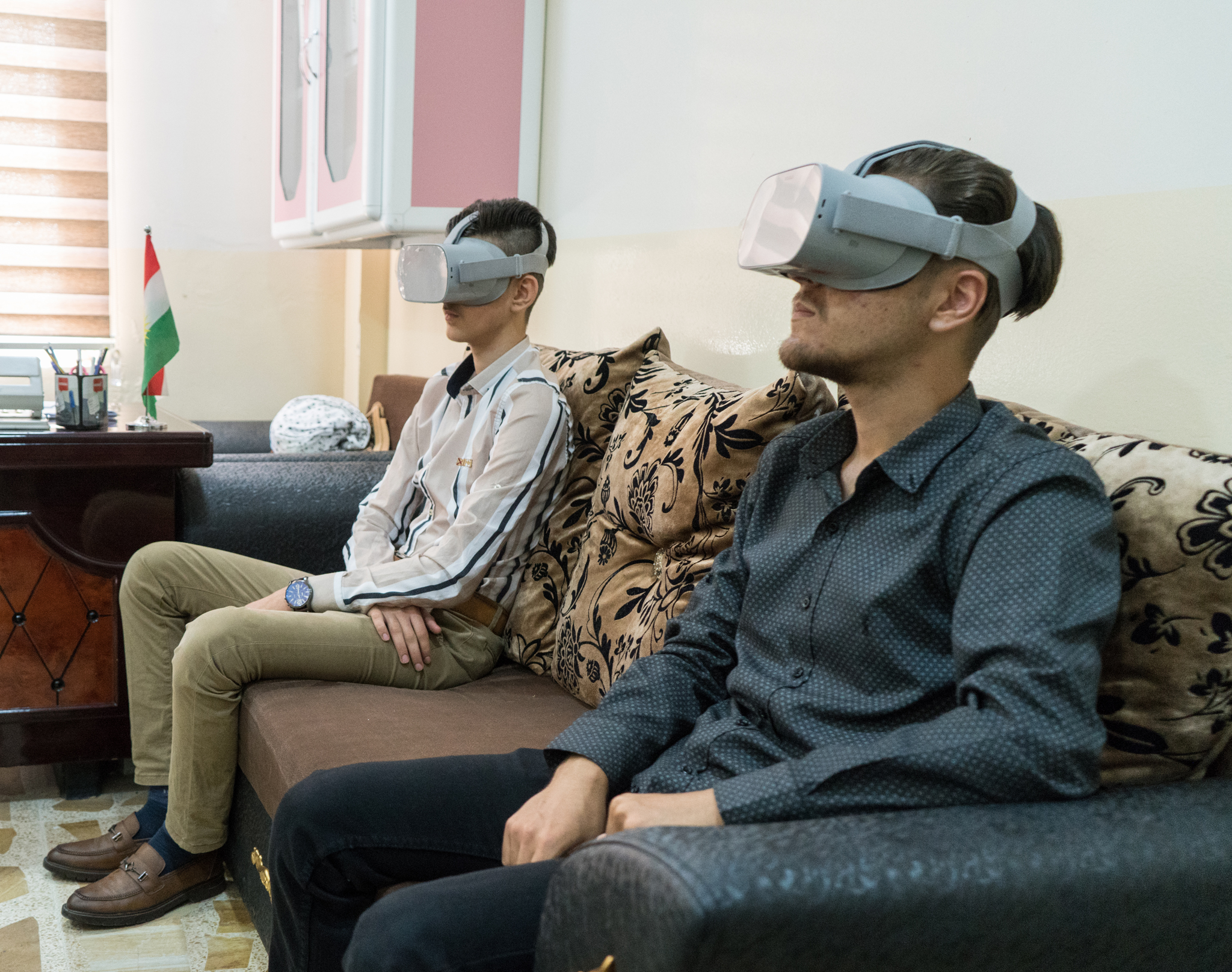 Two young participants in Iraq wear virtual reality goggles which provide visual and audial immersion.