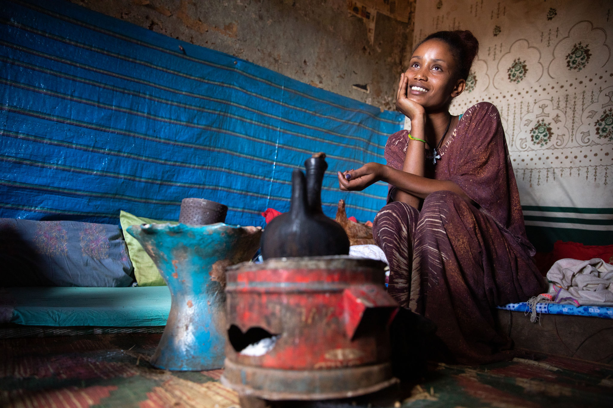 An adult sits and waits for coffee to brew inside her home in Ethiopia