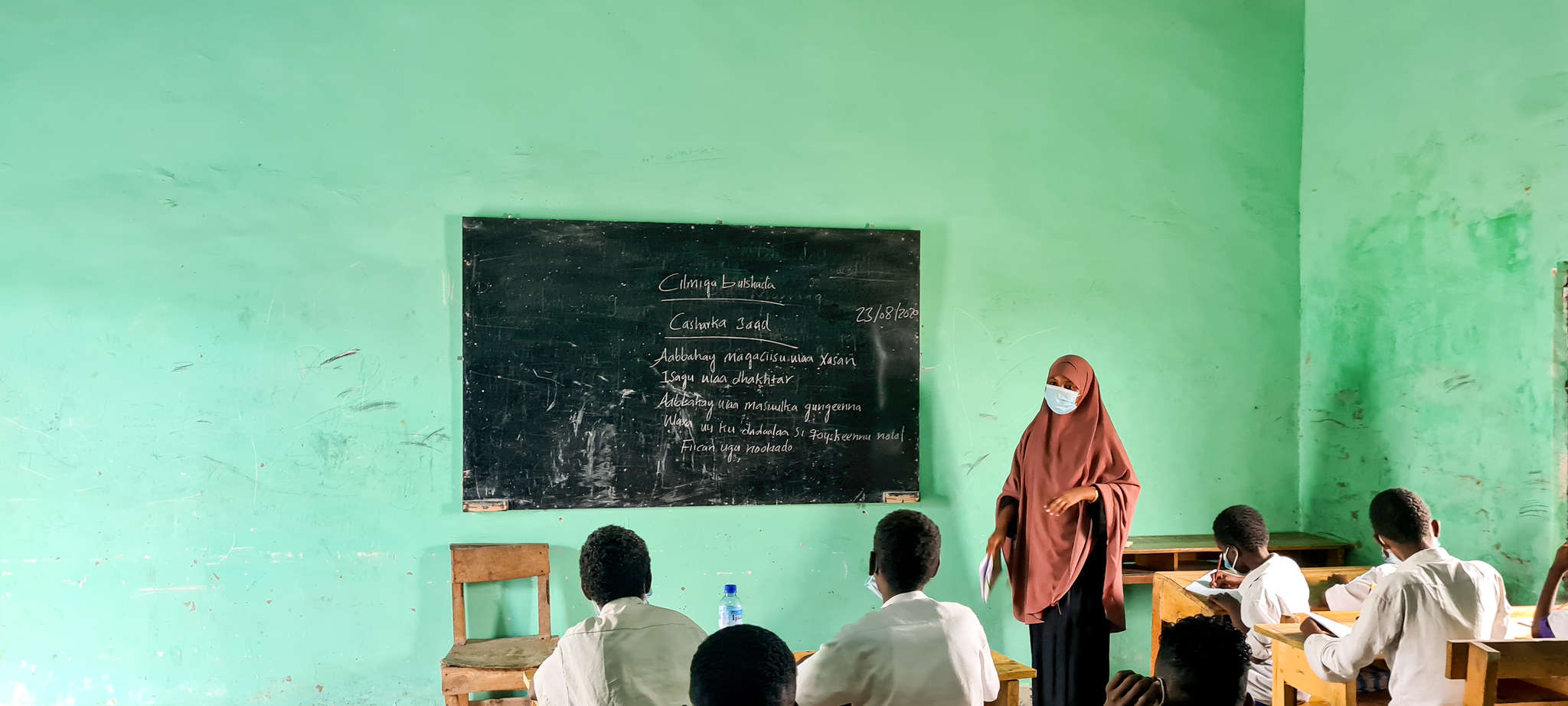 An instructor leads a class while standing at a chalk board.
