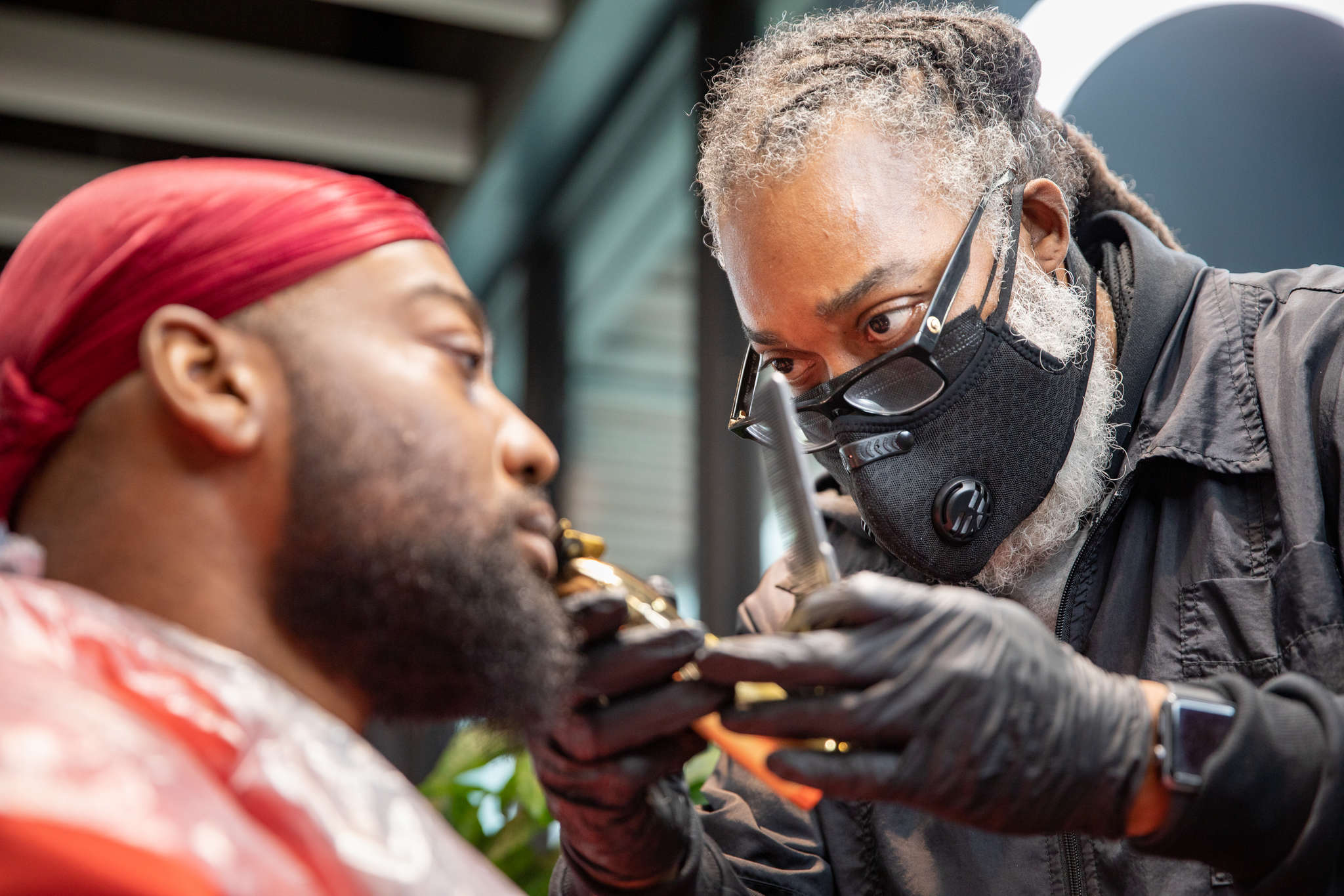 A barber trims the beard of a customer. 