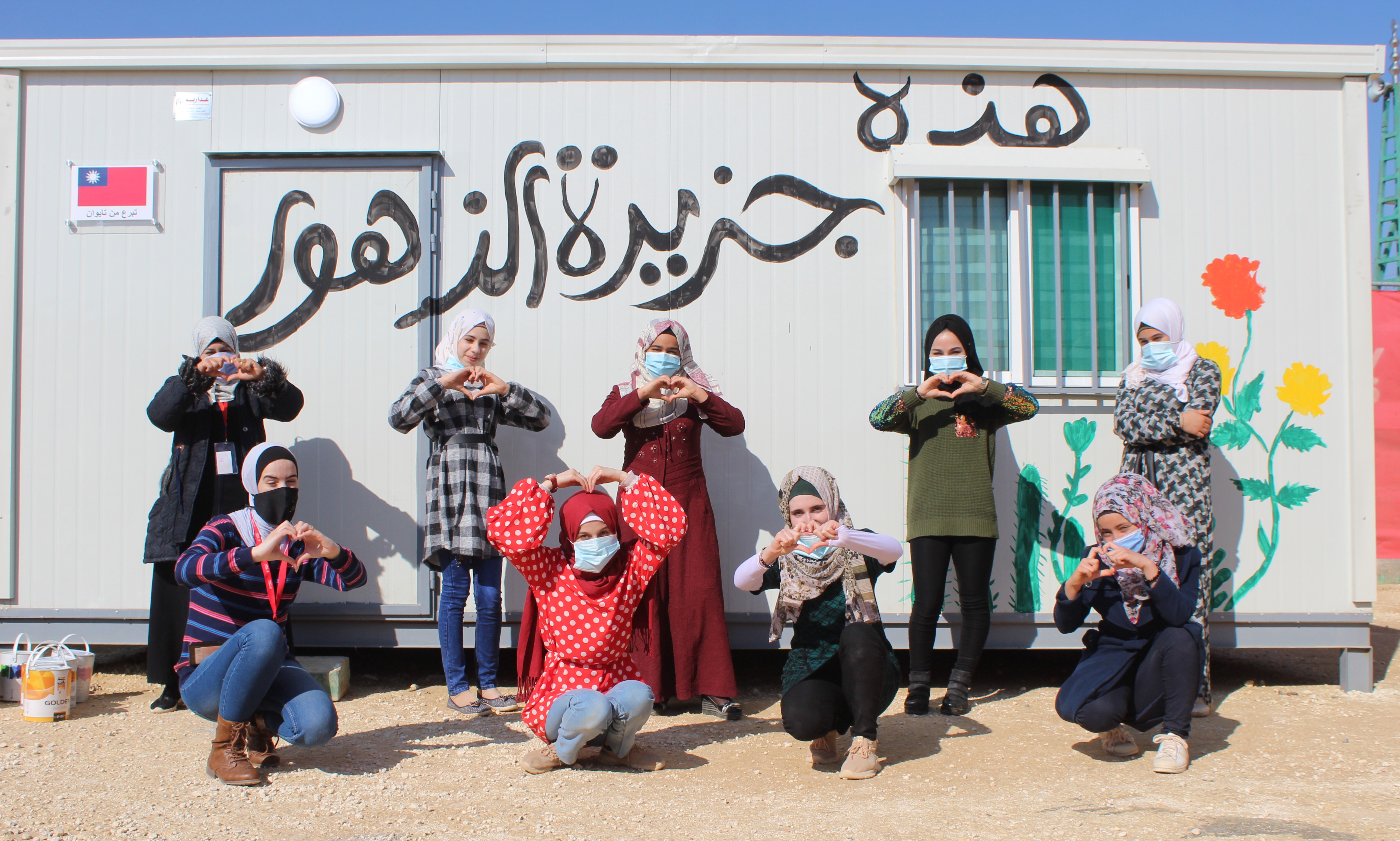 A group of young people pose together outside a temporary structure they designed and decorated themselves.