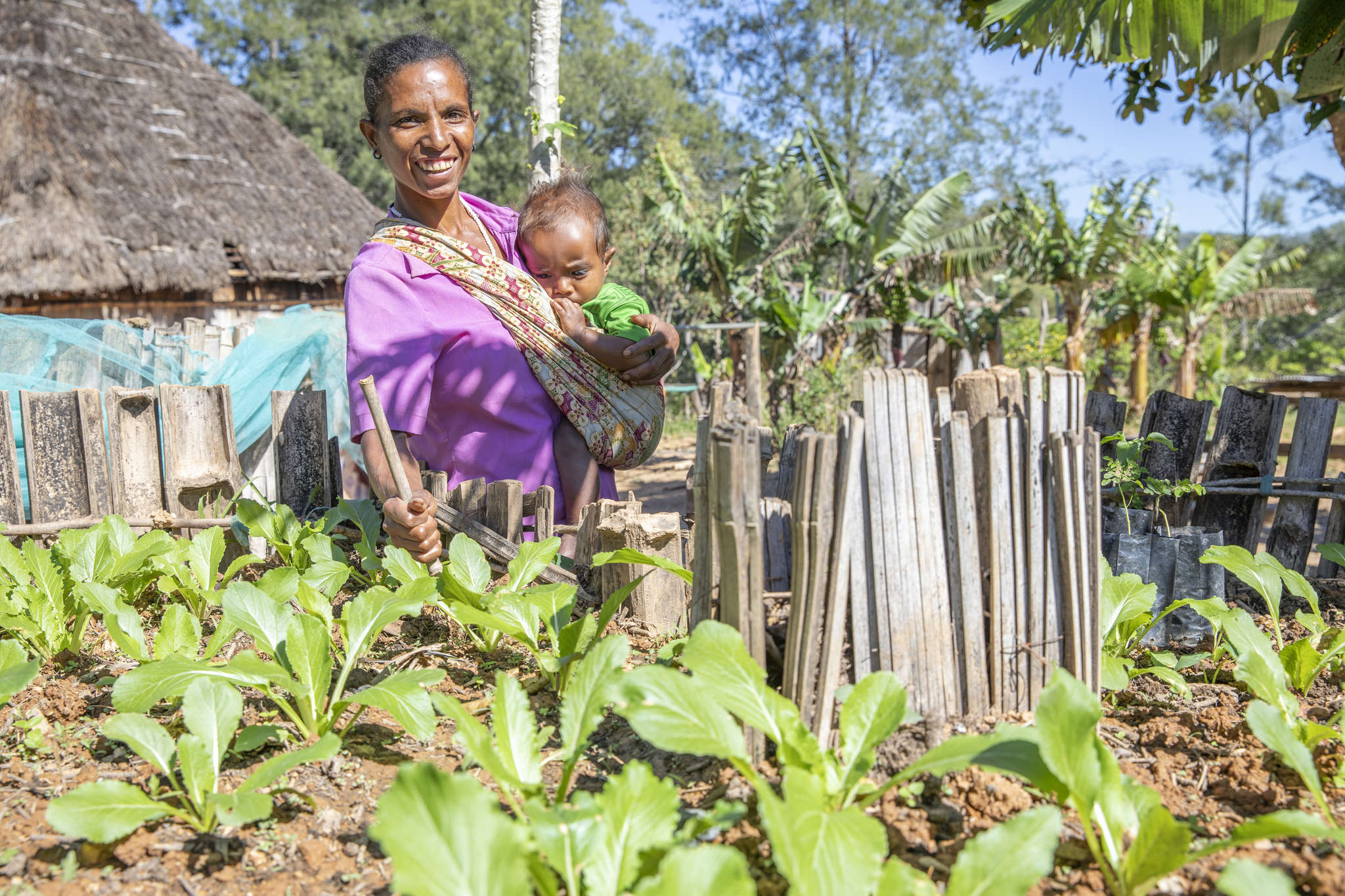 Timor Leste woman in vegetable garden with child.