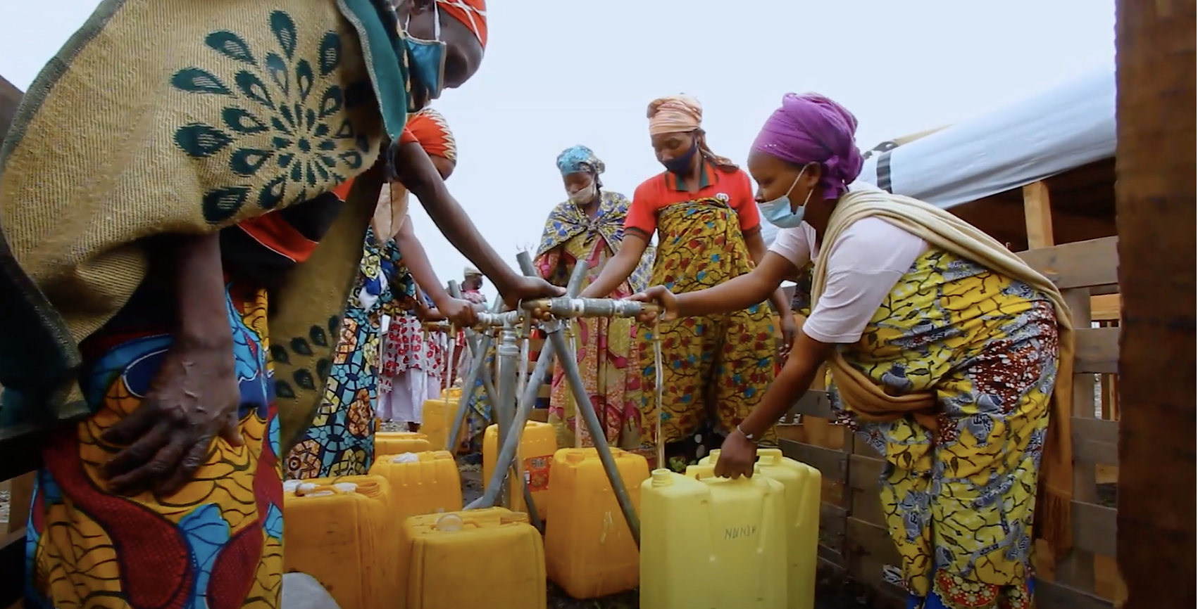A group of people filling jerry cans at a water station.