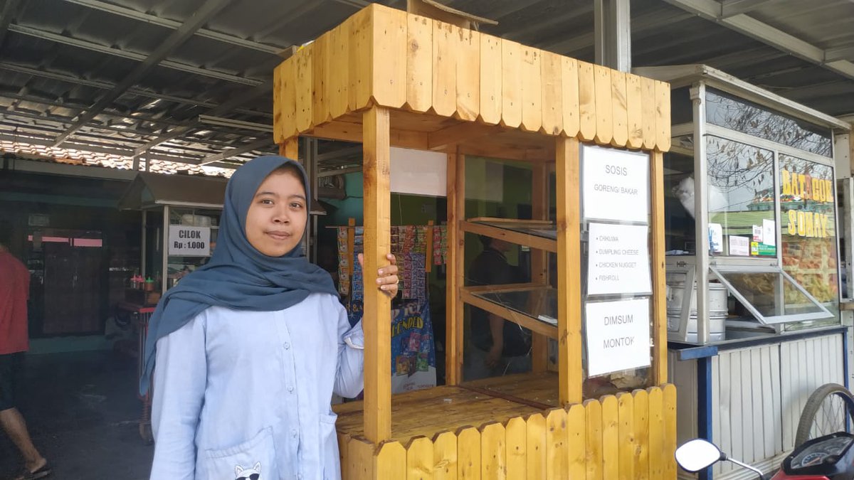 Nour Aulia standing next to her food kiosk business.