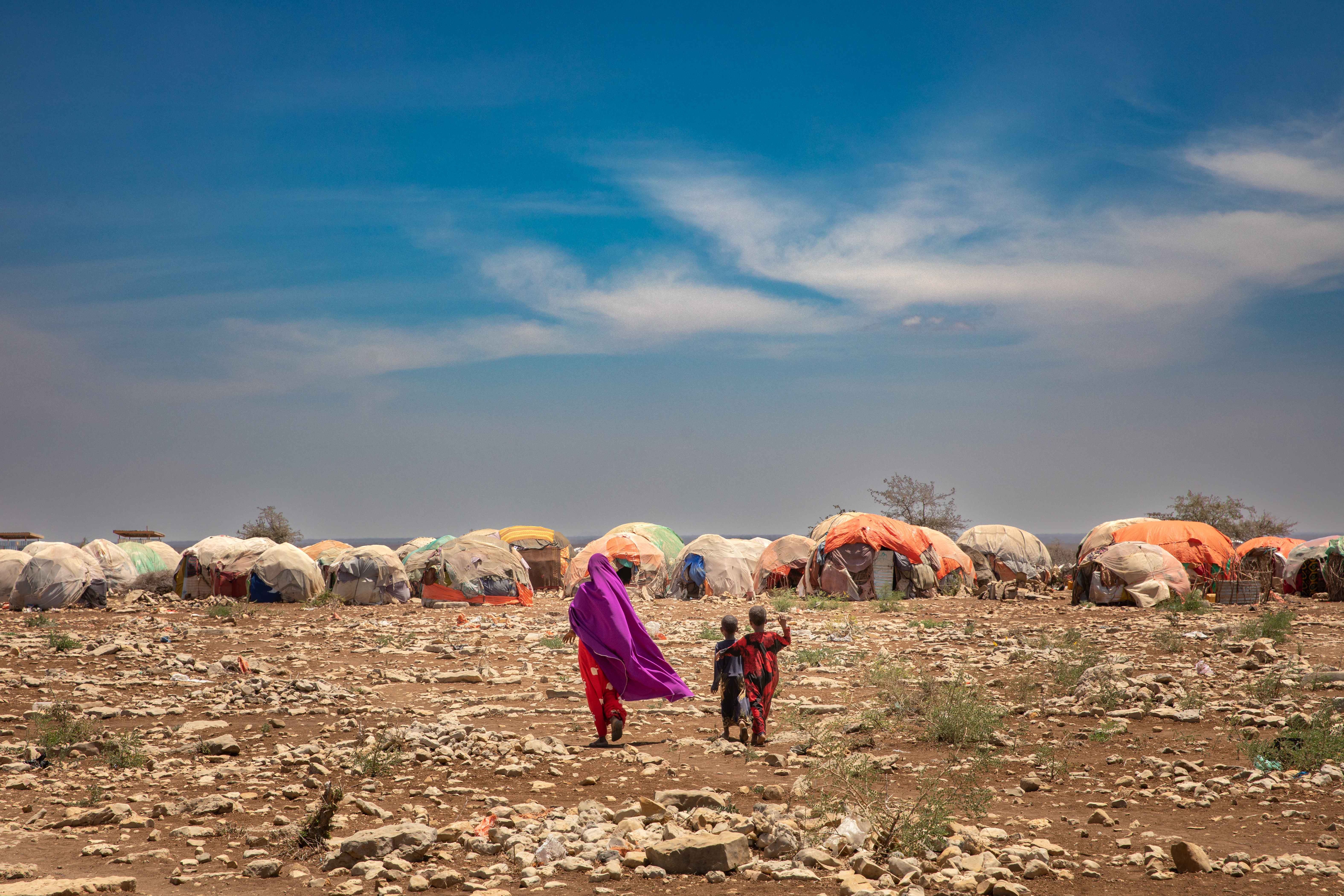 Two people walking towards temporary structures. 