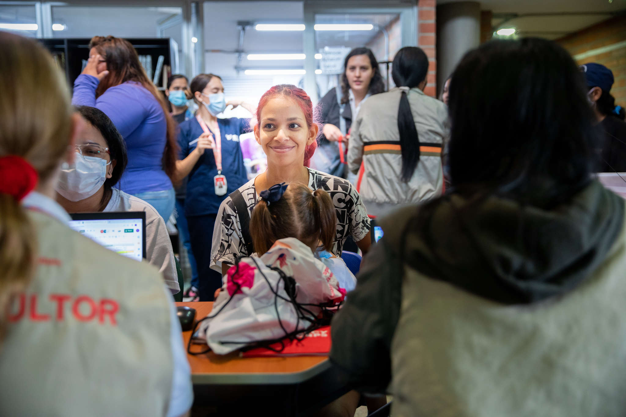 A person holding their child while speaking with Mercy Corps staff at a health clinic in Medellín, Colombia.