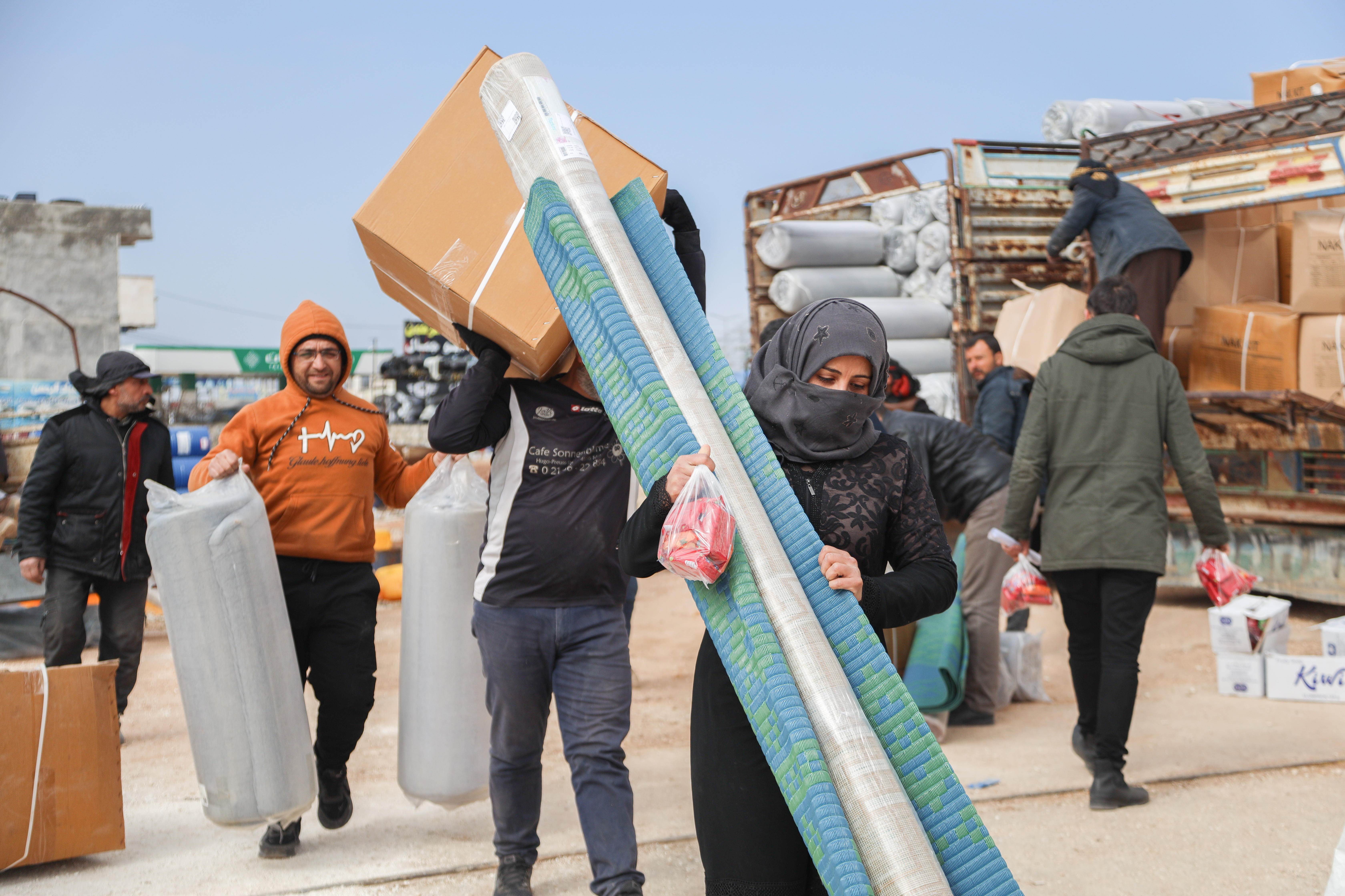 A woman in northwest syria carries emergency kits delivered by mercy corps.