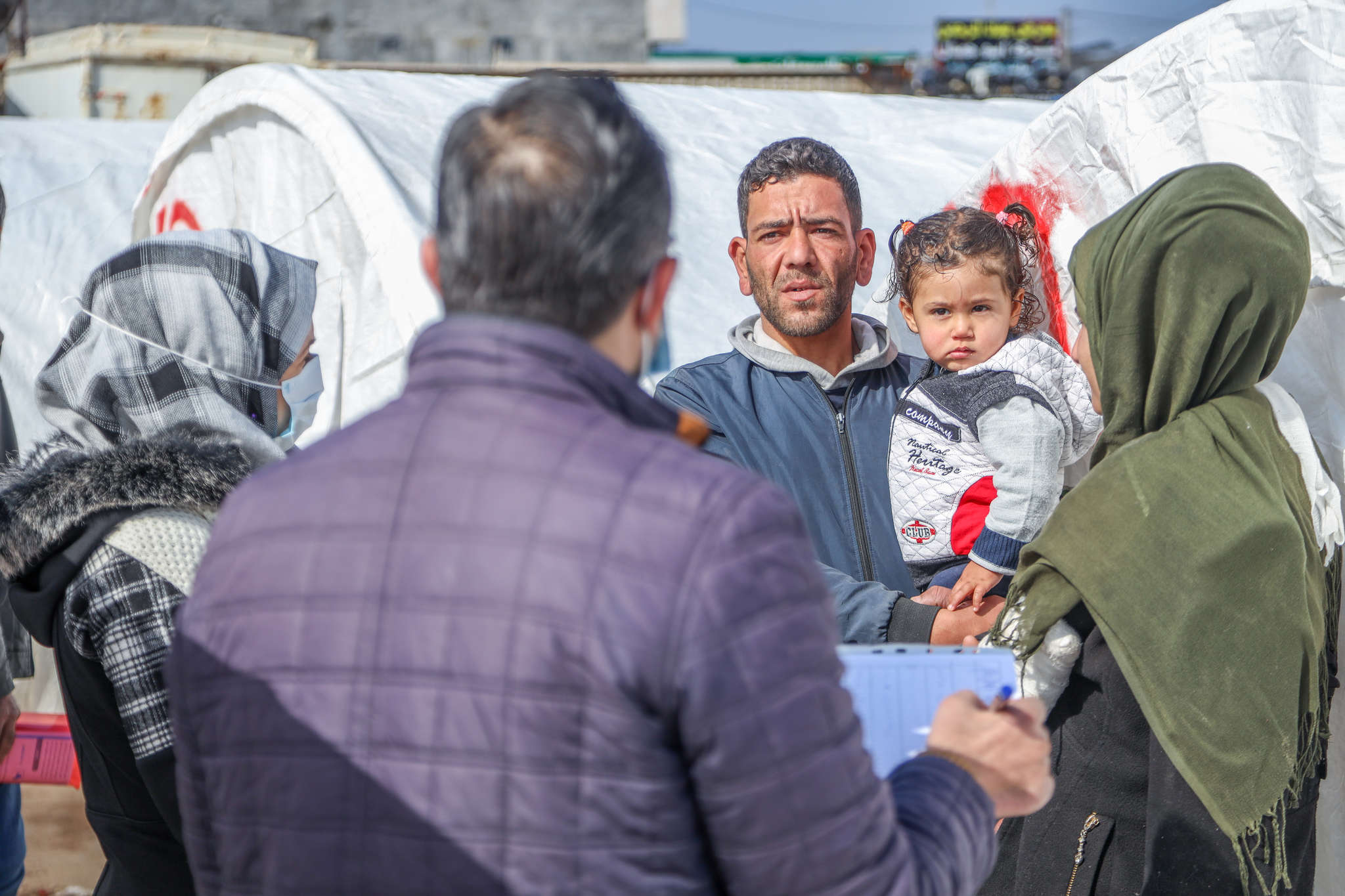 Adults with children speaking with aid workers about receiving emergency supplies.
