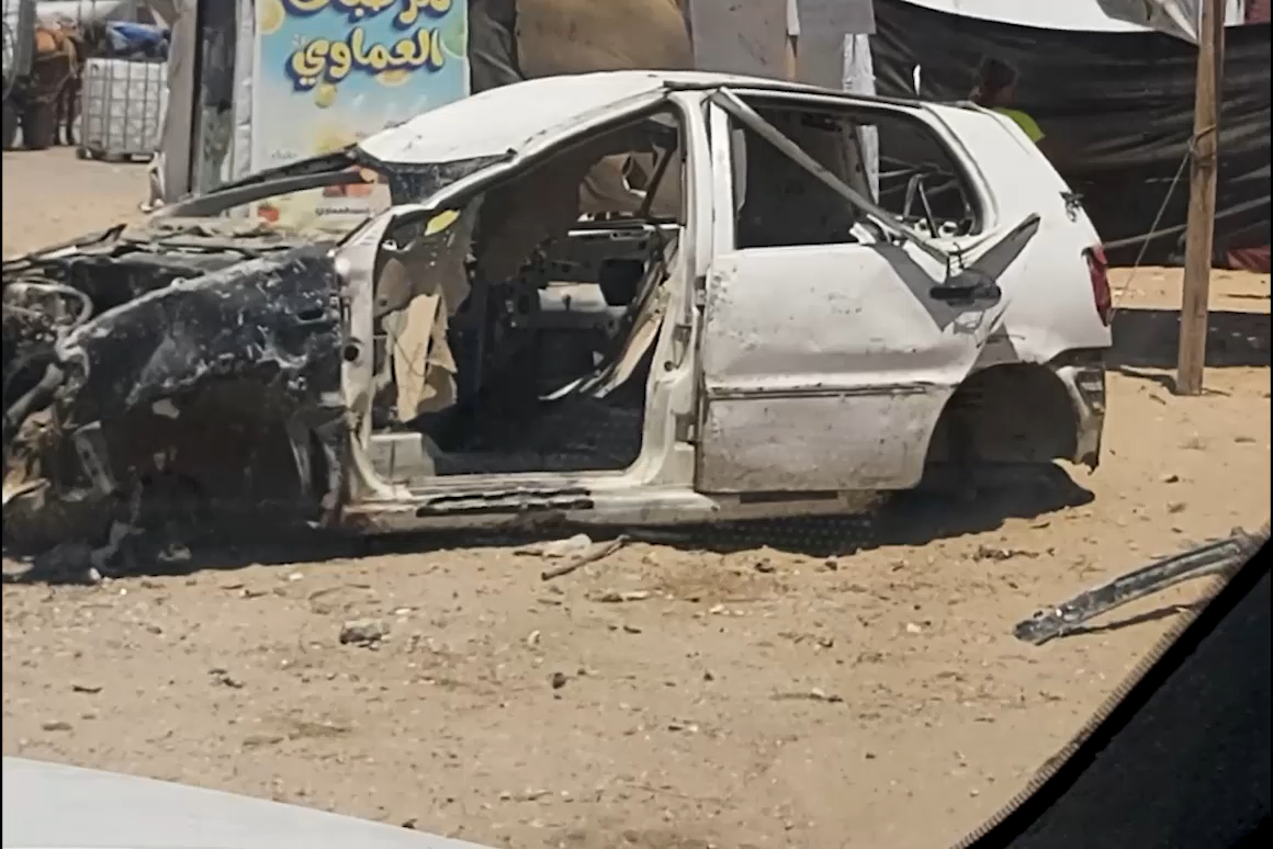 Destroyed automobile in the middle of a street in gaza.
