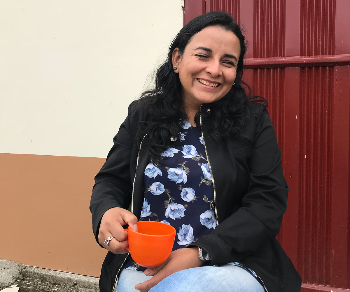 woman holding an orange cup smiling at the camera