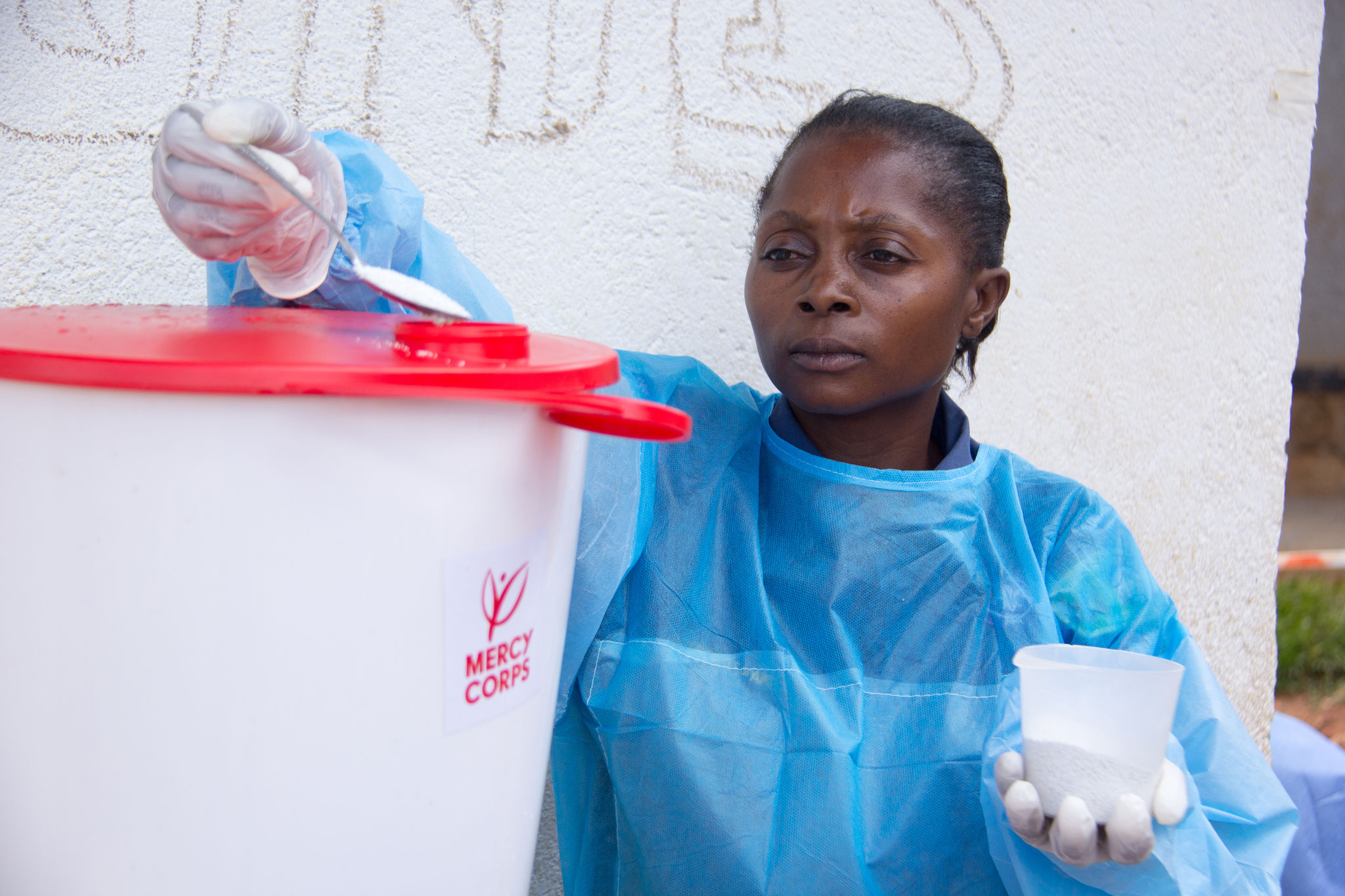 Woman in DR Congo disinfecting a container of water