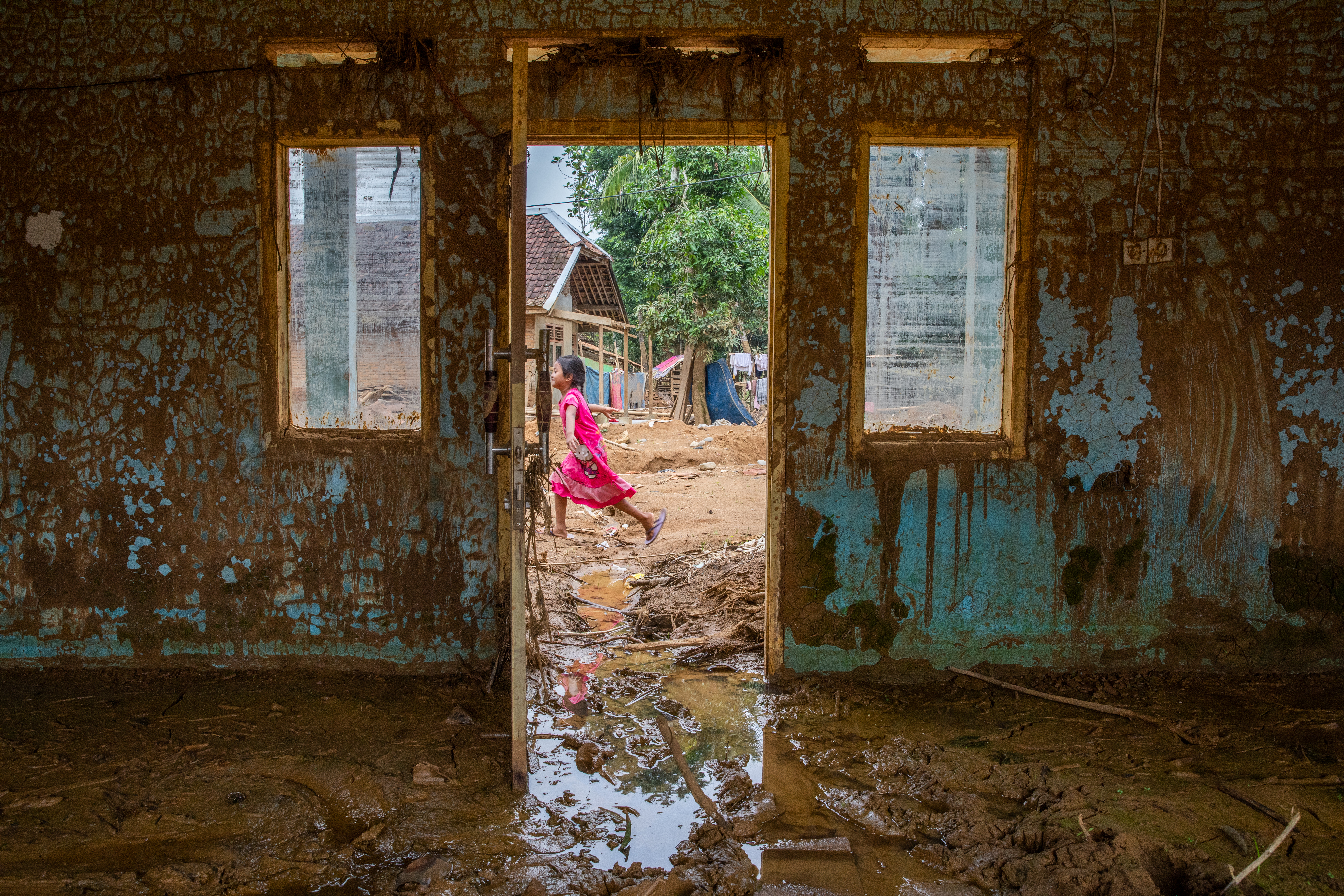 Gladis, 6, walks past a flooded home in Susukan, Java, Indonesia