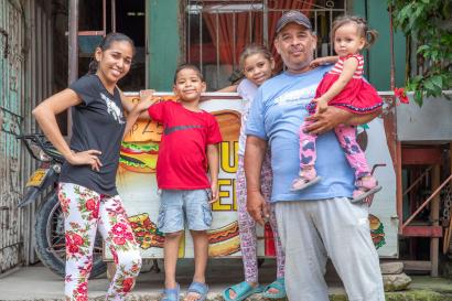 A Mercy Corps’ VenEsperanza program participant standing next to her food cart business with her family.