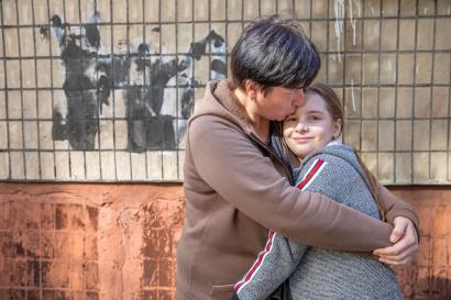 A mother and daughter embracing in front of their temporary apartment.