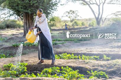 Kenyan woman watering garden.