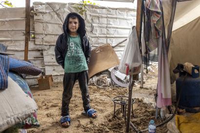 A Palestinian boy stands near an improvised tent