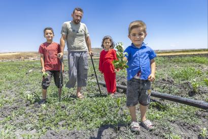 Syrian family standing in agricultural setting.