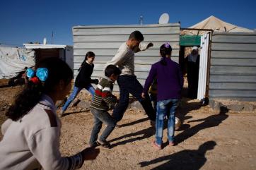 Ibrahim playing soccer with children in the yard