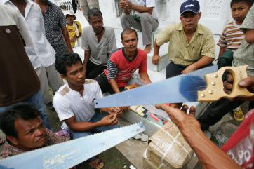 Men receiving saws to help rebuild