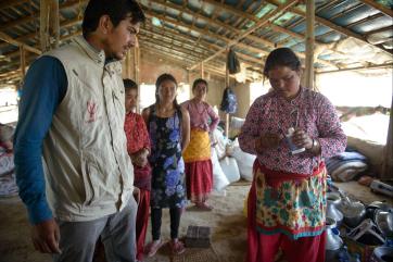 Mercy corps employee teaching people to use water purification treatment