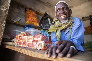 Nigerian man seated at a table smiling at the camera