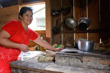 A woman wearing a red dress prepares food in her kitchen in colombia