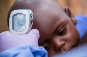 A boy having his temperature taken. a thermometer reads 37.0 degrees c