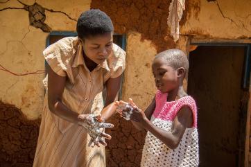 Woman showing child how to wash hands