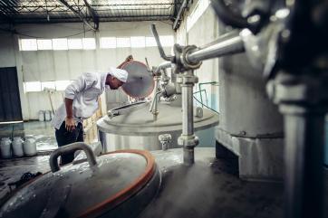 A man looks into a vat of milk in a processing plant in ethiopia