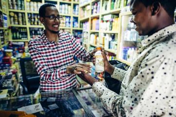 A man purchases the final product, bottled milk, from a shop in ethiopia