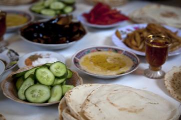 Several small dishes filled with hummus, sliced cucumber and other vegetables, and pita