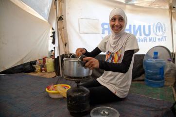 A teenage girl cooks in a tent in zaatari refugee camp