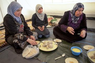 Three syrian refugee women sit down to enjoy a meal in jordan
