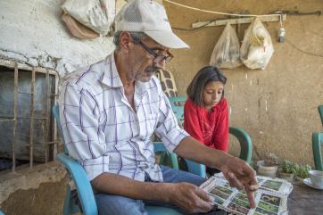 Abu goubran and his daughter sitting side by side, looking at a seed catalog