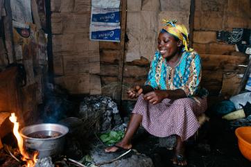 A woman cooks beans over a fire in dr congo