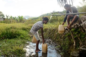 Girls filling water containers at a spout