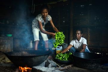 A girl putting vegetables into a pot in timor-leste