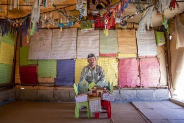 In jordan, a syrian refugee holds a model he made of his dream house while sitting in a classroom covered in posters and recycled materials the children gathered.
