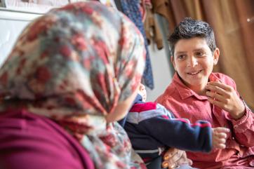 A young particpant sits with their mother and sibling in za’atari, jordan.